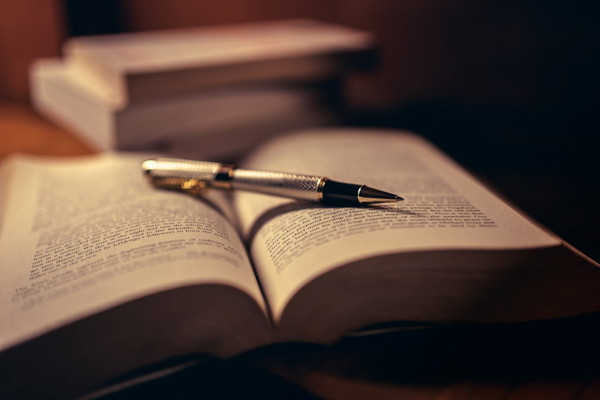 A printed page of text lying on a wooden desk in low, warm light.